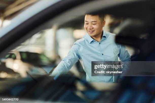 glücklicher asiatischer verkäufer, der in einem autohaus arbeitet. - autoglas stock-fotos und bilder