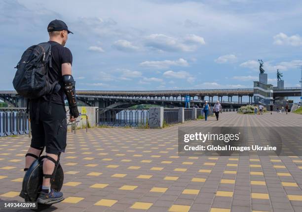 Man rides a self balancing one wheel electric scooter along Poshtova Square near the Dnipro River waterfront on May 21, 2023 in Kyiv, Ukraine. Russia...