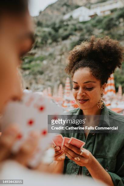 happy woman enjoy a game of cards on a beach. - solitaire stock pictures, royalty-free photos & images