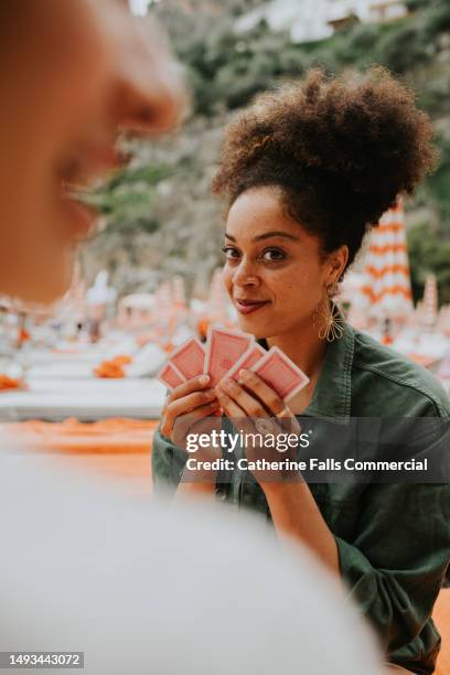 happy woman enjoy a game of cards on a beach. - solitaire stock pictures, royalty-free photos & images