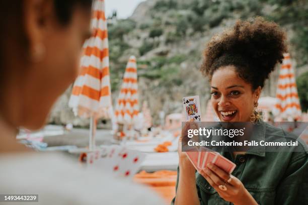 happy woman enjoy a game of cards on a beach. - solitaire stock pictures, royalty-free photos & images