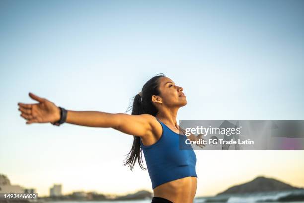 young sporty woman inhaling and feeling the breeze on the beach - dreams stock pictures, royalty-free photos & images
