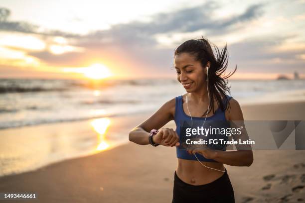 junge sportliche frau, die am strand läuft - sand clock stock-fotos und bilder