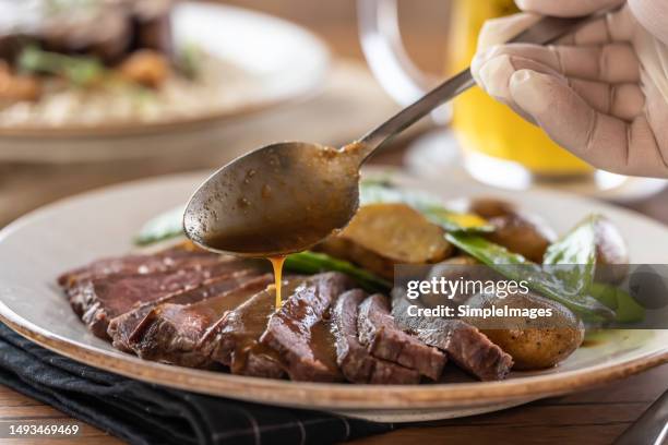 the chef finishes the beef steak on the plate, pours demi glace sauce over the meat. - wagyu rump steak stock pictures, royalty-free photos & images