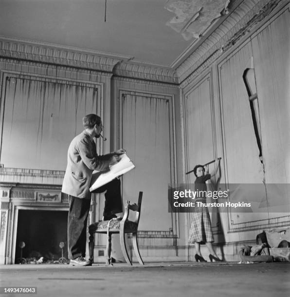 Man and a woman pictured in the living room of a run-down town house in Eaton Square, London, before conversion into self-contained flats, circa...
