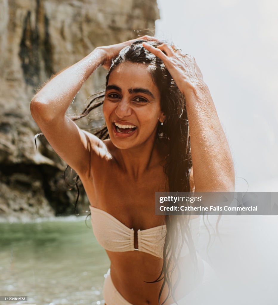 A woman pushes her long wet hair out of her face as she enjoys a dip in the ocean