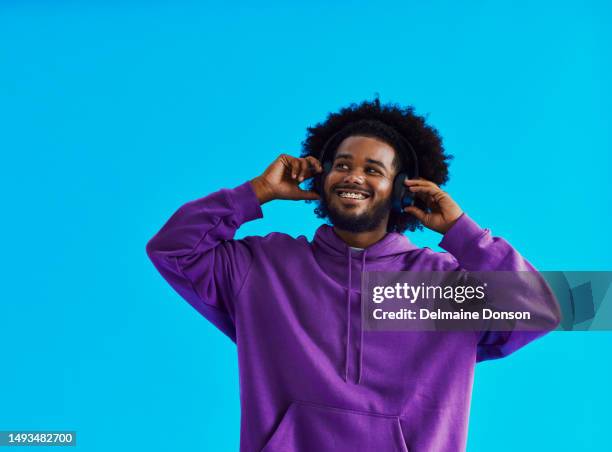 homem negro jovem com um penteado afro usando um moletom roxo, de pé com seu fone de ouvido ligado enquanto sorri com aparelhos dentários com espaço de cópia, foto de banco - big hair - fotografias e filmes do acervo