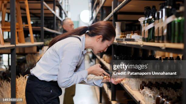 good inventory management system keeps inventory organized and allows small businesses growth sustainable. senior small business owner using barcode scanner scan at the bottle to check stock inventory in the storehouse at home decor shop with the customer - pricing strategy stock pictures, royalty-free photos & images