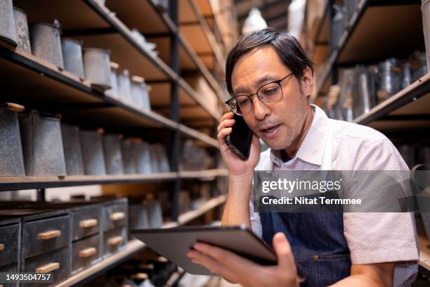 make it easy for people to reach your product to increasing your customer retention. a japanese furniture shop owner talking with a customer via smartphone about product feedback and advice in a storehouse to improve product and service. - royalty rate stock pictures, royalty-free photos & images