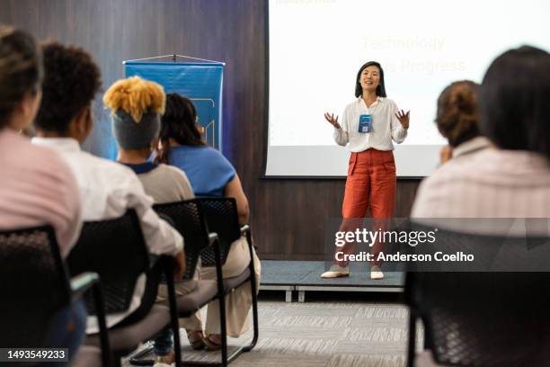 asian woman giving lecture to business audience - palestra imagens e fotografias de stock