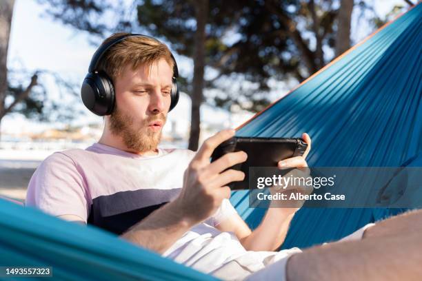 an amazed man playing on the beach - computerspiel konsole stock-fotos und bilder