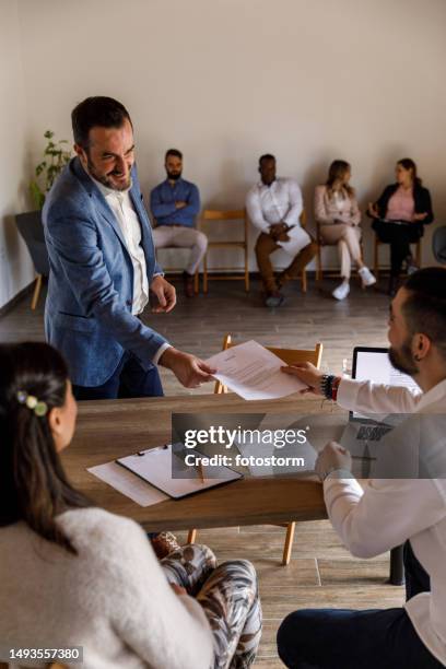 confident businessman submitting his resume at the beginning of a job interview meeting - file sharing stock pictures, royalty-free photos & images