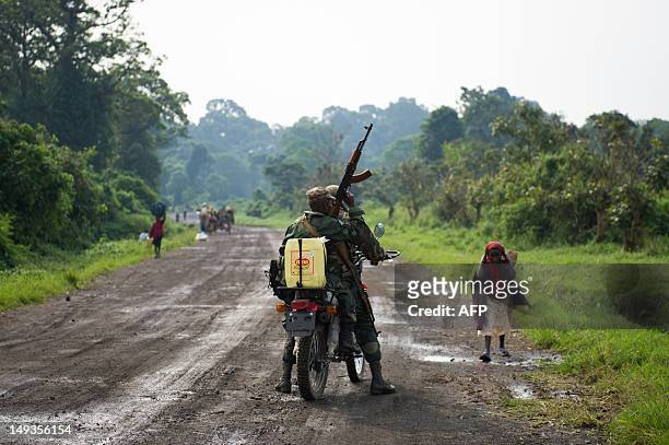Two Congolese government army soldiers mount a motorbike on the outskirts of Kibumba, as civilians flee clashes in Rugari in the east of the...