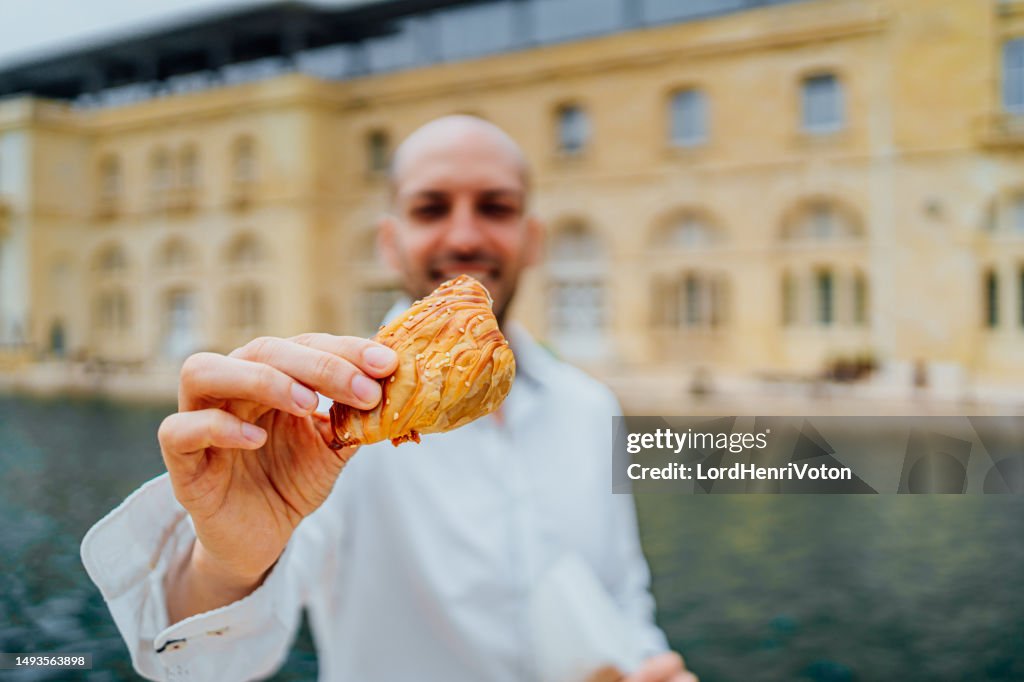 Man holding traditional Maltese pastry Pastizzi in Valletta