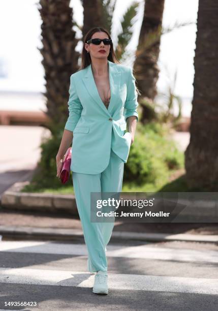 Rebecca Kunikowski seen wearing Sketchers sneaker shoes, a turquoise suit pants and matching turquoise blazer jacket, a pink bag and black sunglasses...