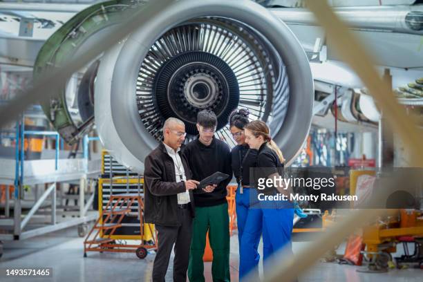 aircraft engineers in meeting by jet engines in aircraft maintenance factory - aerospace engineering stock pictures, royalty-free photos & images
