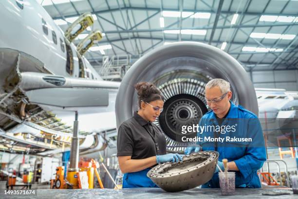 aircraft engineer instructing apprentice in aircraft maintenance factory - aerospace engineering stock-fotos und bilder