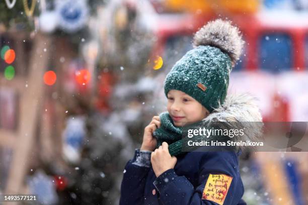 portrait of a pretty girl on the background of christmas decorations in winter.a child in a winter hat and jacket at a new year's market - city year stock-fotos und bilder