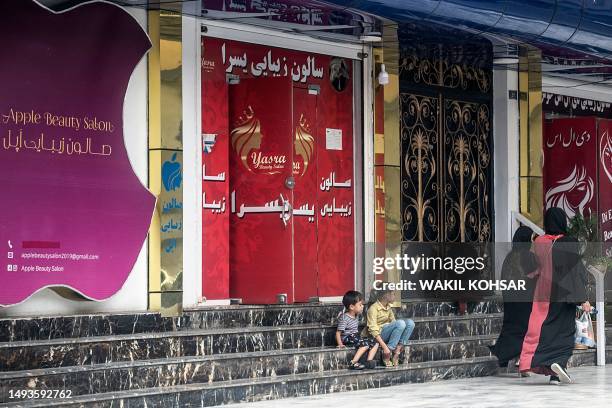 Women walks past a beauty salon at the Shahr-e Naw area in Kabul on July 4, 2023. Afghanistan's Taliban authorities have ordered beauty parlours...