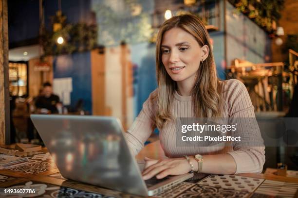 woman using laptop while working at cafe - working behind laptop stockfoto's en -beelden