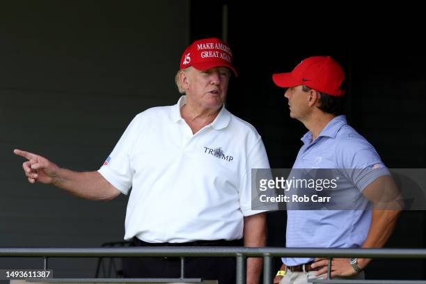 Former US President Donald Trump talks with former White House Deputy Press Secretary Hogan Gidley from a box on the 18th green during day one of the...