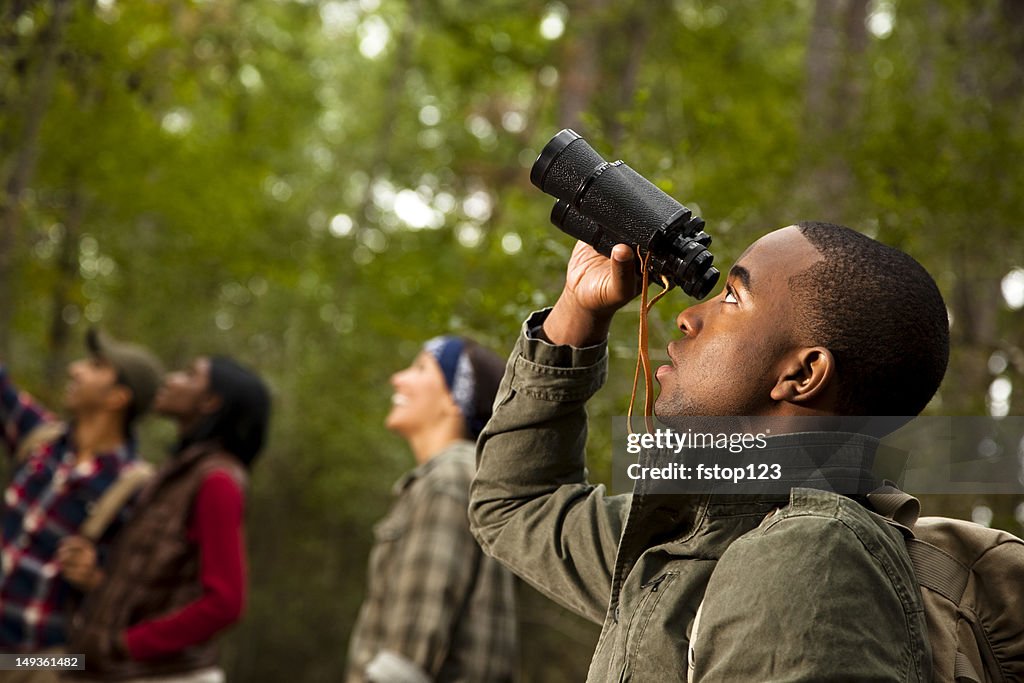 Group of friends camping and hiking using binoculars. Bird watching.