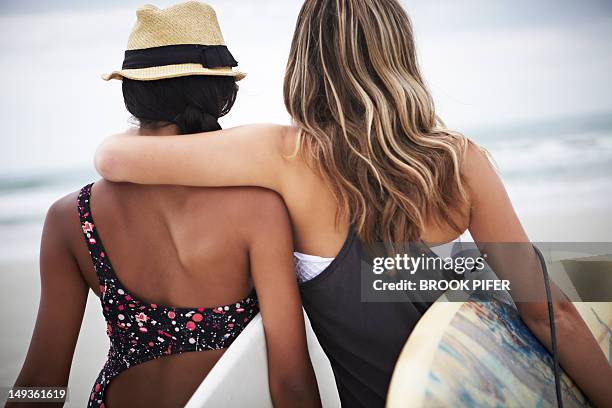 two young women holding surfboards on beach - swimwear singlet stock pictures, royalty-free photos & images