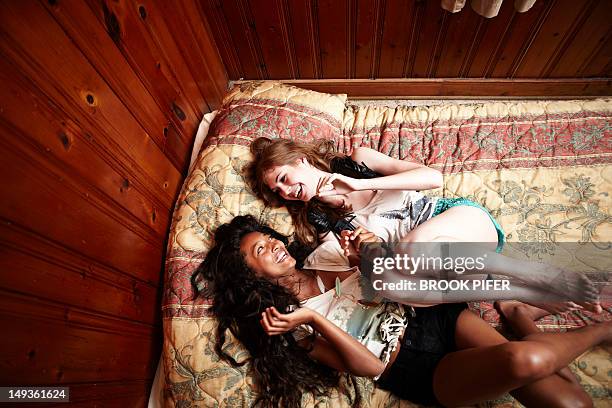 two young women laughing on bed - beste freunde teenager stock-fotos und bilder