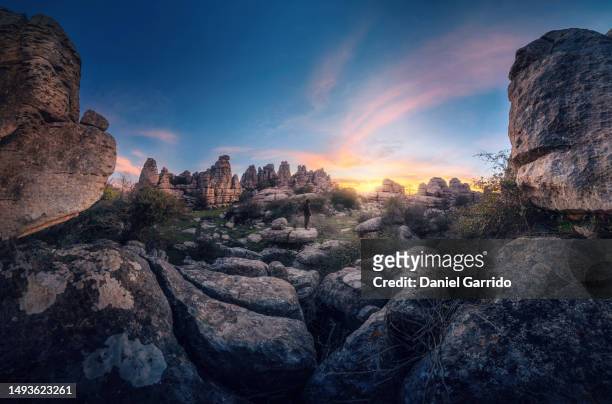 the grandeur of torcal de antequera at dawn, a person facing the panoramic grandeur of torcal de antequera, a panoramic perspective of the ancestral immensity of torcal de antequera - paraje natural torcal de antequera stock pictures, royalty-free photos & images