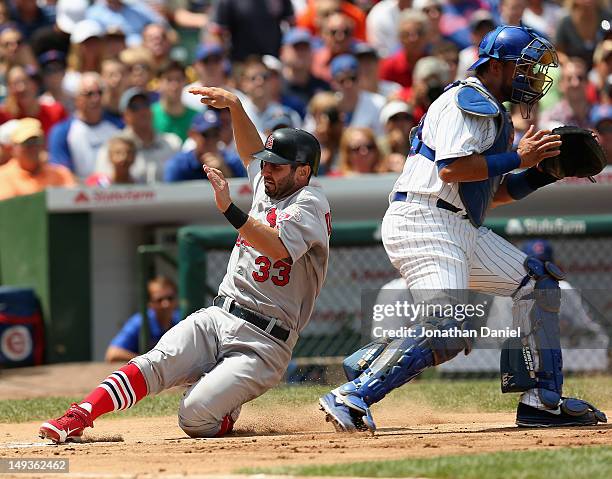 Daniel Descalso of the St. Louis Cardinals slides safely into home plate as Geovany Soto of the Chicago Cubs waits for the ball at Wrigley Field on...