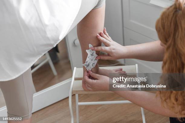 tattoo artist removing the tracing paper from a leg in a tattoo studio - decal stock pictures, royalty-free photos & images
