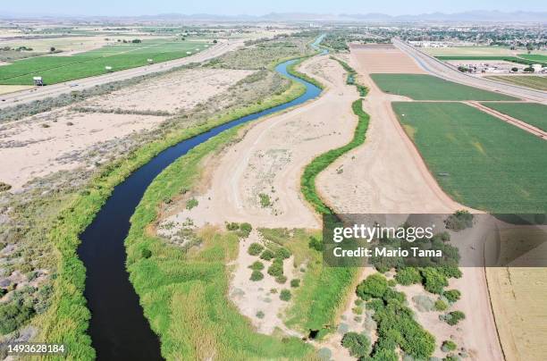 In an aerial view, the long-depleted Colorado River is swollen by winter snowmelt water as it flows near farmland along the border between Arizona...
