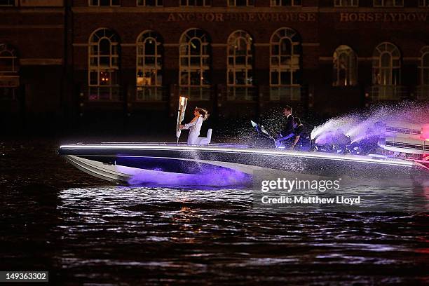 David Beckham passes under Tower Bridge driving a speedboat named 'Max Power' which carries the Olympic Torch carried by torchbearer Jade Bailey on...