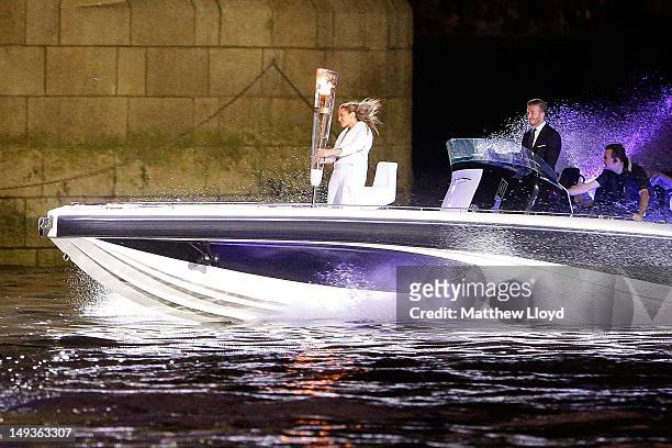 David Beckham passes under Tower Bridge driving a speedboat named 'Max Power' which carries the Olympic Torch carried by torchbearer Jade Bailey on...