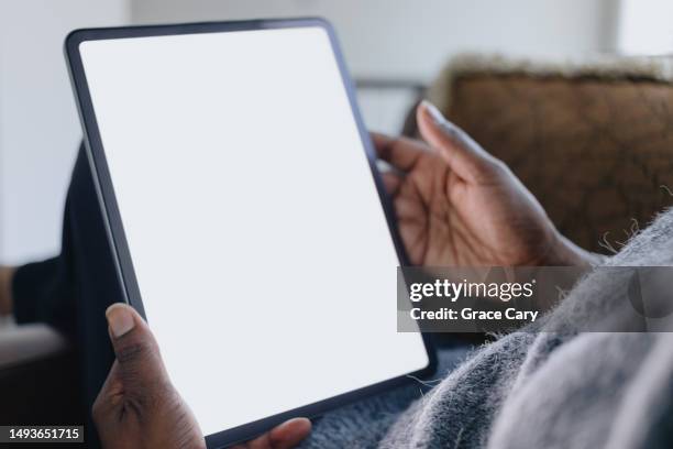 woman uses digital tablet with blank screen while relaxing at home - tablet screen stockfoto's en -beelden