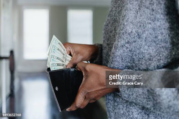 woman inserts cash into wallet - geld und finanzen stock-fotos und bilder