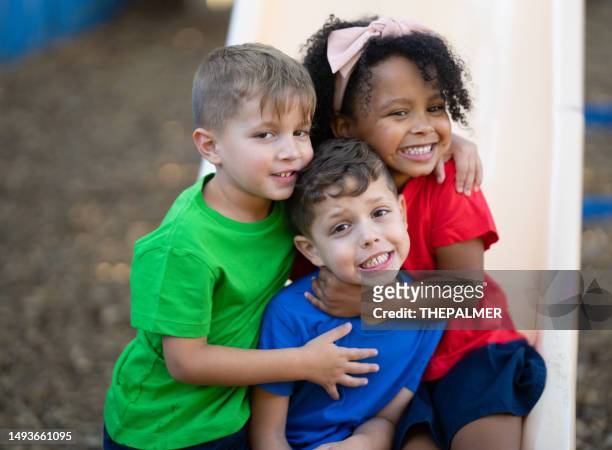 tres niños en edad preescolar se divierten jugando en el patio de su guardería - empatía fotografías e imágenes de stock