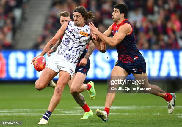 Luke Jackson of the Dockers kicks whilst being tackled by md5during the round 11 AFL match between Narrm Football Club / Melbourne Demons and...