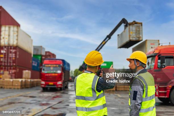 zwei asiatische arbeitsverwalter auf der werft tauschten vor ort befehle aus - dockarbeiter stock-fotos und bilder