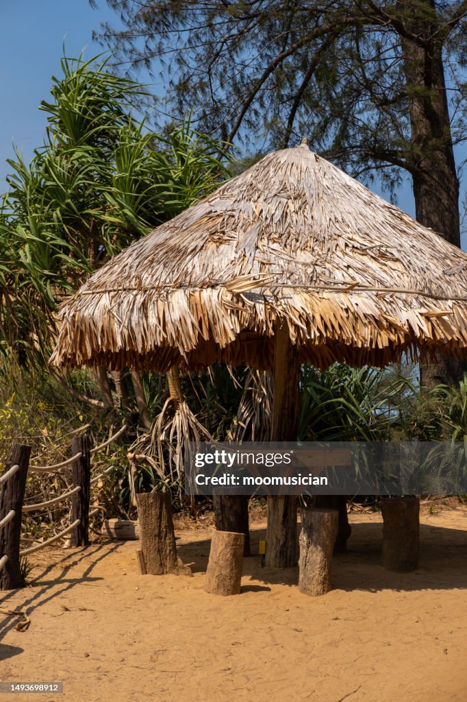Seating under a wooden hut shelter, located by the sea.