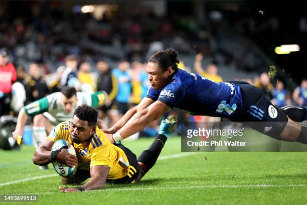 Kini Naholo of the Hurricanes scores a try under pressure from Caleb Clarke of the Blues during the round 14 Super Rugby Pacific match between Blues...