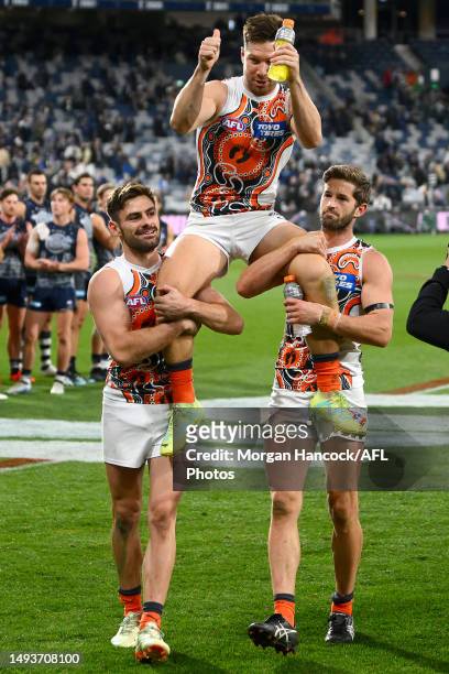 Stephen Coniglio and Callan Ward chair Toby Greene of the Giants off after his 200th game during the round 11 AFL match between Geelong Cats and...