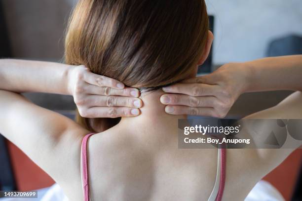 rear view of young woman having neck pain. - muscle cramps stock pictures, royalty-free photos & images