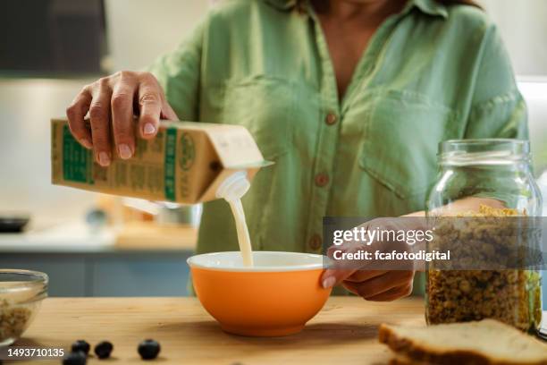 woman pouring soy milk into a bowl for healthy breakfast - cereal boxes stock pictures, royalty-free photos & images