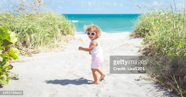 adorable mixed race toddler headed to the ocean on an idyllic summer beach - sunny florida stock pictures, royalty-free photos & images