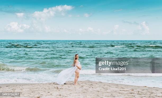 beautiful pregnant woman with exposed belly in flowing dress in an idyllic beach location, hope anticipation and new life - beautiful perfection exposed lady stock pictures, royalty-free photos & images