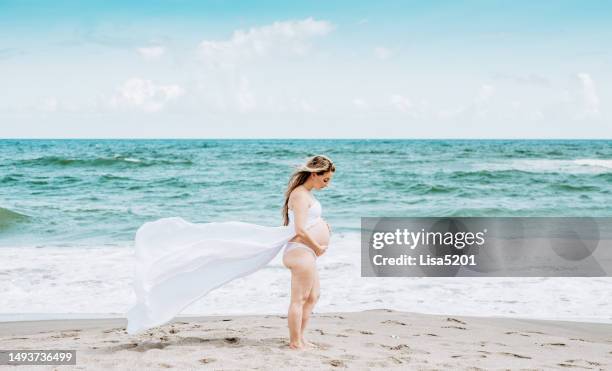 beautiful pregnant woman with exposed belly in flowing dress in an idyllic beach location, hope anticipation and new life - beautiful perfection exposed lady stock pictures, royalty-free photos & images