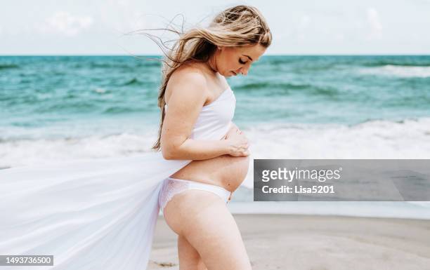 beautiful pregnant woman with exposed belly in flowing dress in an idyllic beach location, hope anticipation and new life - beautiful perfection exposed lady stock pictures, royalty-free photos & images