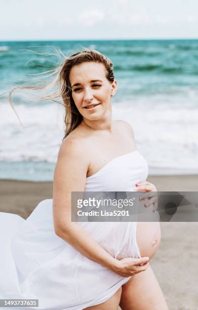 beautiful pregnant woman with exposed belly in flowing dress in an idyllic beach location, hope anticipation and new life - beautiful perfection exposed lady bildbanksfoton och bilder