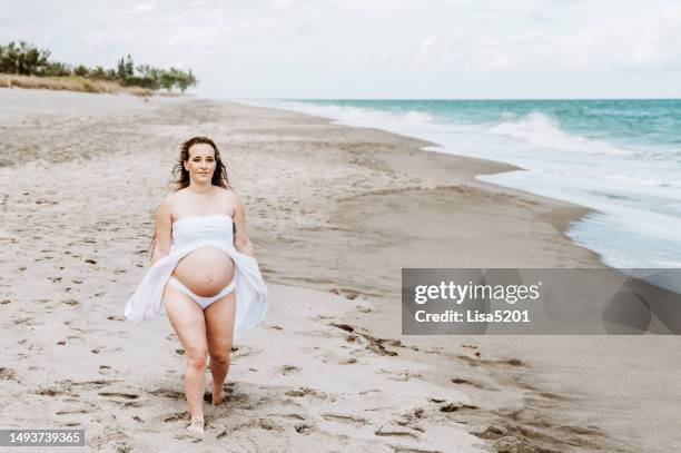 beautiful pregnant woman with exposed belly in flowing dress in an idyllic beach location, hope anticipation and new life - beautiful perfection exposed lady stock pictures, royalty-free photos & images